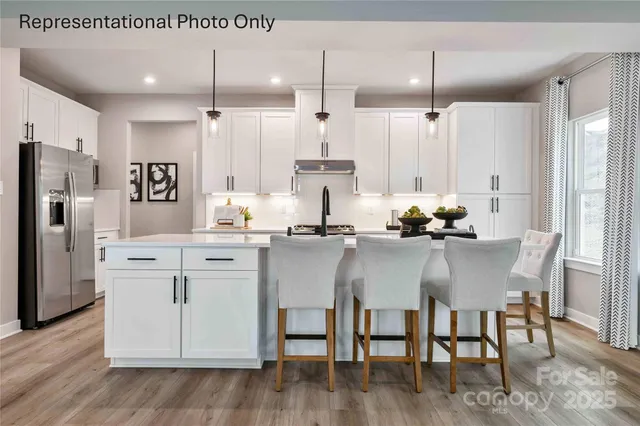 a kitchen with stainless steel appliances kitchen island granite countertop a table chairs and a refrigerator