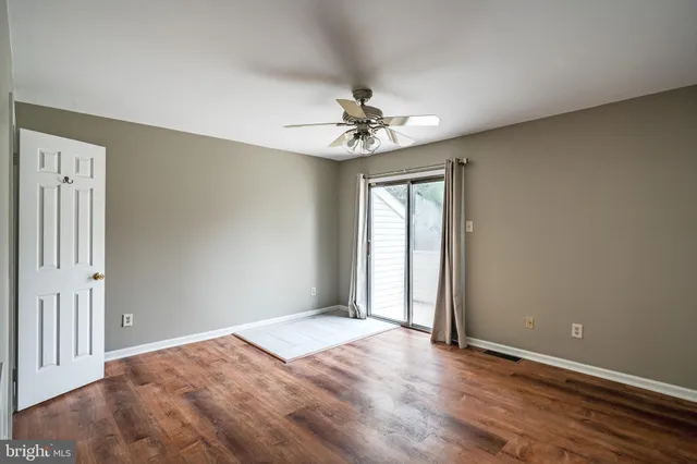 an empty room with wooden floor fan and windows
