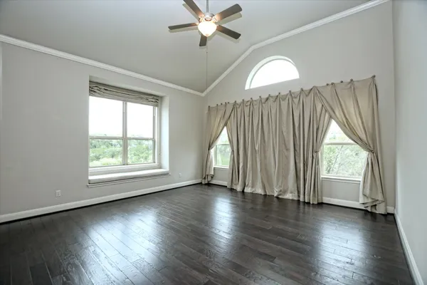 an empty room with wooden floor chandelier fan and windows