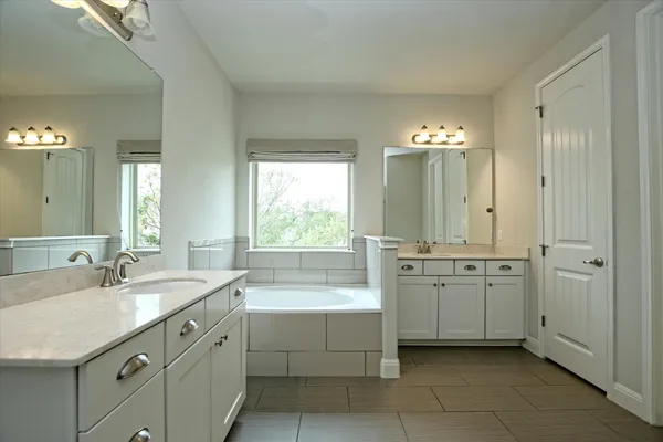 a spacious bathroom with a double vanity sink a large mirror and a bathtub
