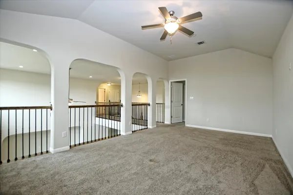 an empty room with chandelier fan and windows