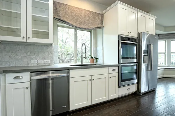 a kitchen with stainless steel appliances granite countertop a sink and cabinets with wooden floor