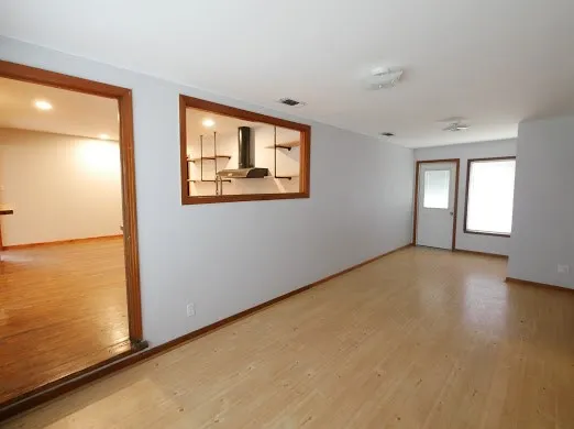 a view of an empty room with window and wooden floor