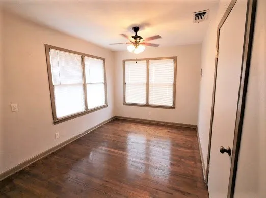 a view of an empty room with a window and wooden floor