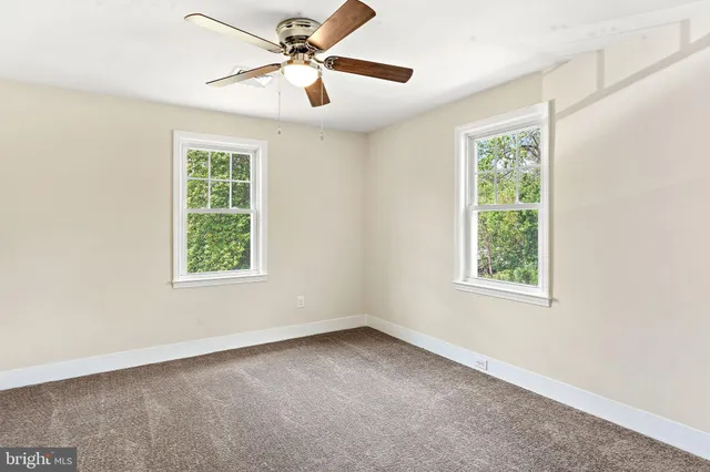 an empty room with a window and a fan