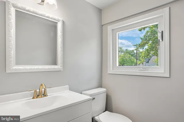 a bathroom with a toilet sink vanity and mirror