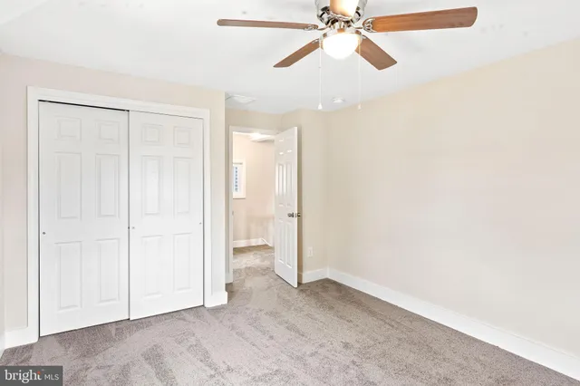 an empty room with closet and a chandelier fan