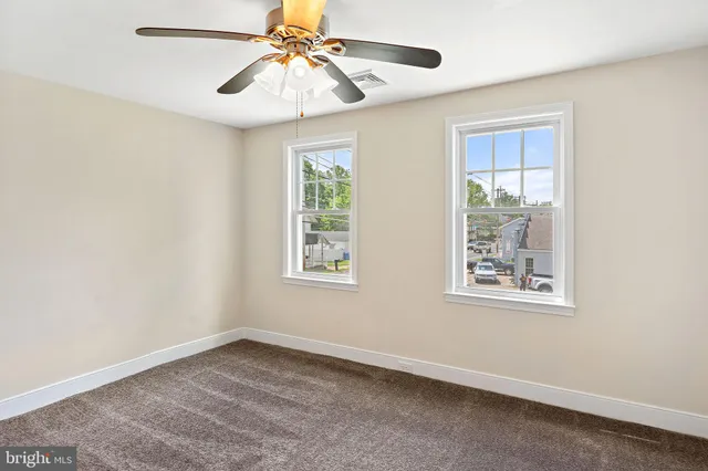 an empty room with a window and a fan