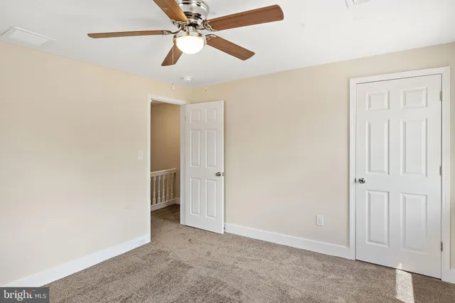 an empty room with closet and a chandelier fan