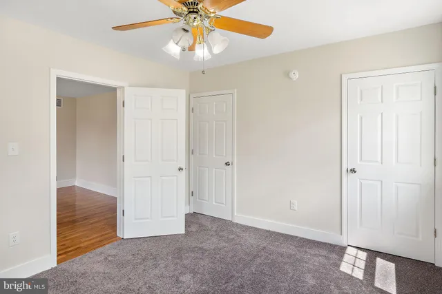 a view of an empty room and chandelier fan