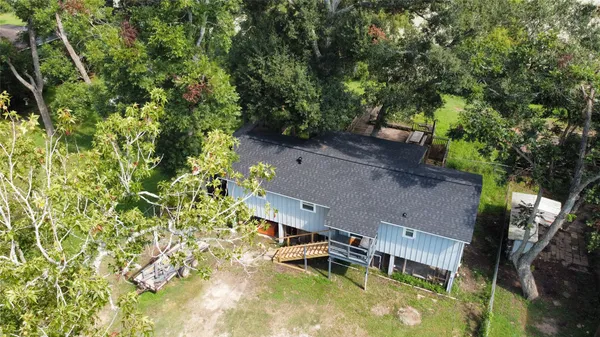 an aerial view of a house with swimming pool and large trees
