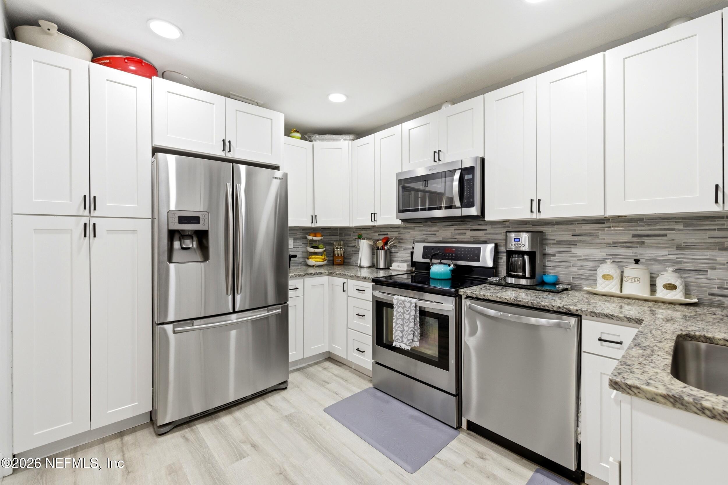 1955 Layton Road Jacksonville, FL 32211 - Photo 15 of 35 a kitchen with stainless steel appliances granite countertop a refrigerator stove a sink and dishwasher with wooden floor