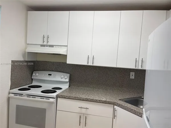 a kitchen with granite countertop white cabinets and white appliances
