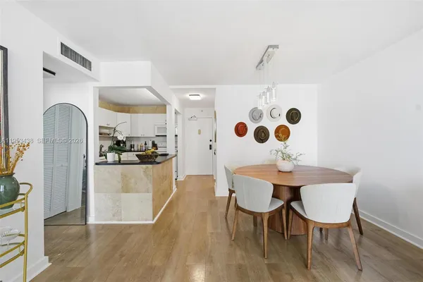 a kitchen with stainless steel appliances kitchen island granite countertop a dining table chairs and a refrigerator