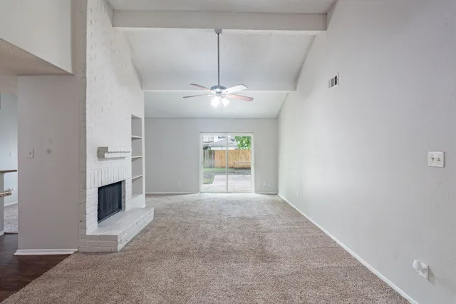 an empty room with windows and fireplace