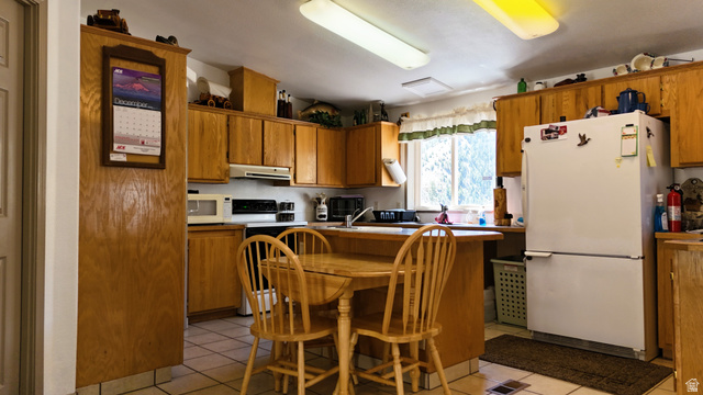 7500 Spring Canyon Road Helper, UT 84526 - Photo 79 of 83 Kitchen featuring white appliances, wood finish cabinets, light countertops, and a breakfast bar area