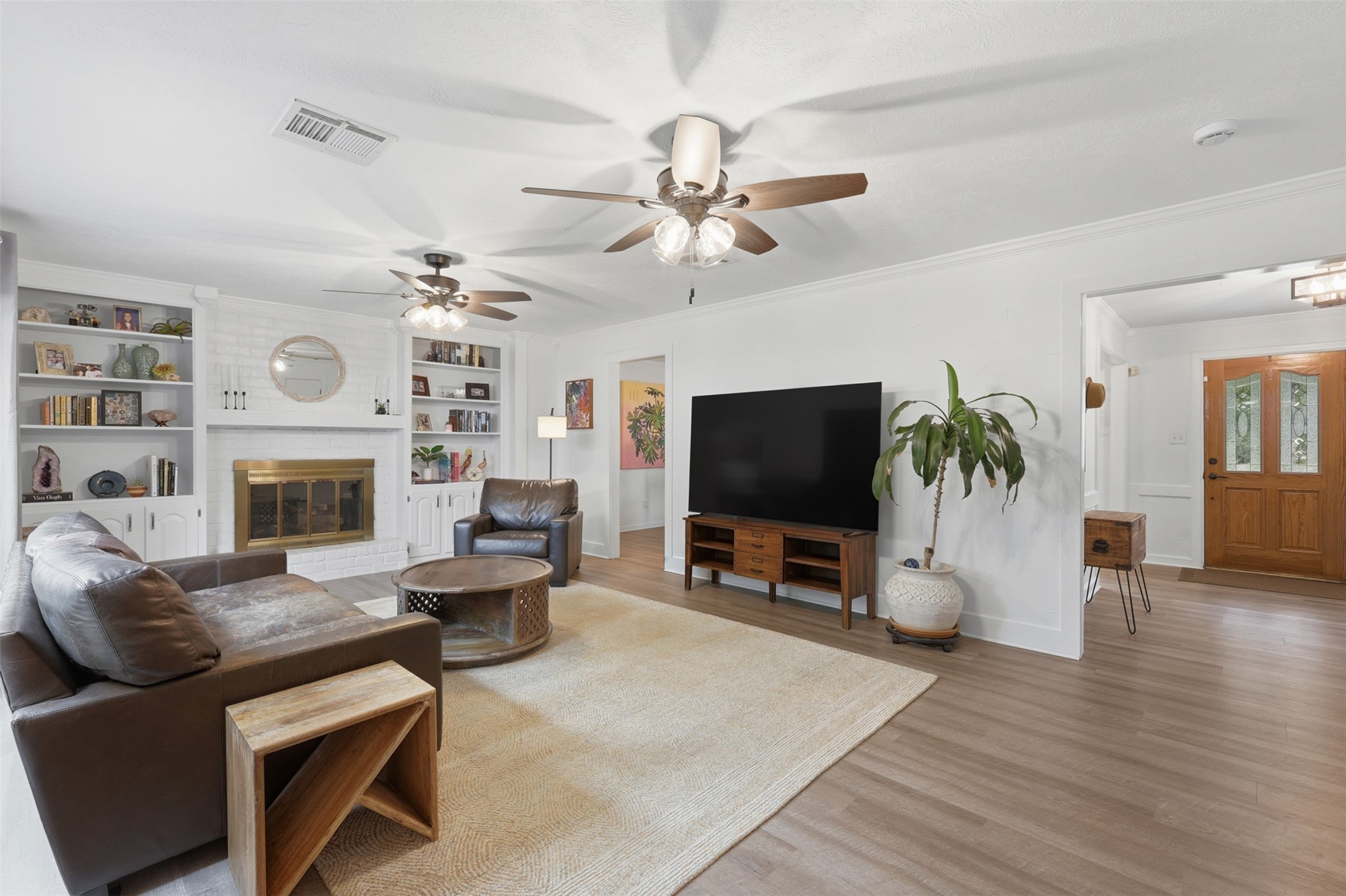 6126 Hickorycrest Drive Spring, TX 77389 - Photo 10 of 50 Spacious living room with a cozy fireplace, built-in shelves, and a ceiling fan for comfort.