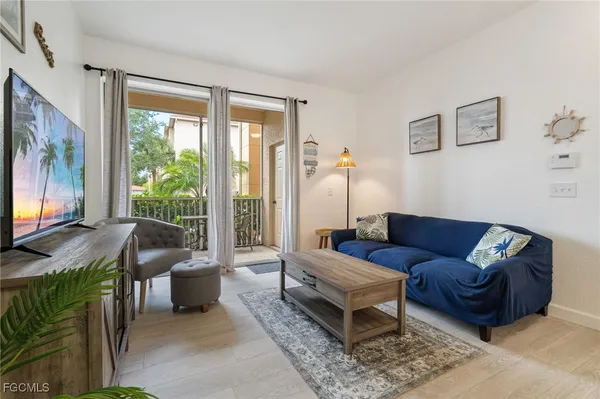 a living room with furniture a flat screen tv and a floor to ceiling window