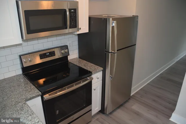 a kitchen with granite countertop a stove and a microwave
