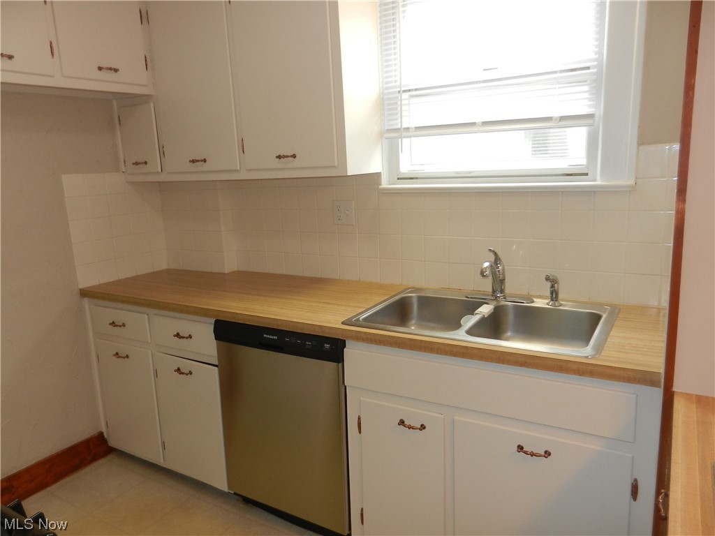 60 East Wilbeth Road Akron, OH 44301 - Photo 6 of 20 Kitchen with white cabinets, stainless steel dishwasher, backsplash, and light floors