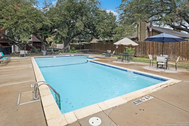 a view of a swimming pool with chairs and an umbrella