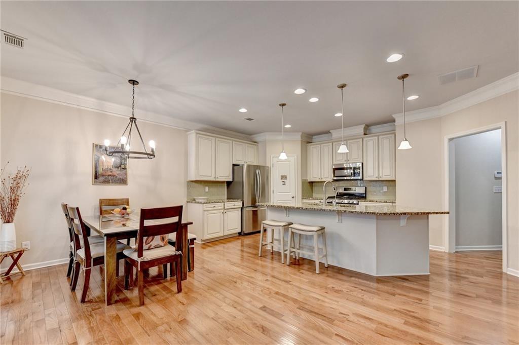 2455 Matlin Way Buford, GA 30519 - Photo 15 of 58 a kitchen with stainless steel appliances kitchen island granite countertop a dining table chairs and white cabinets