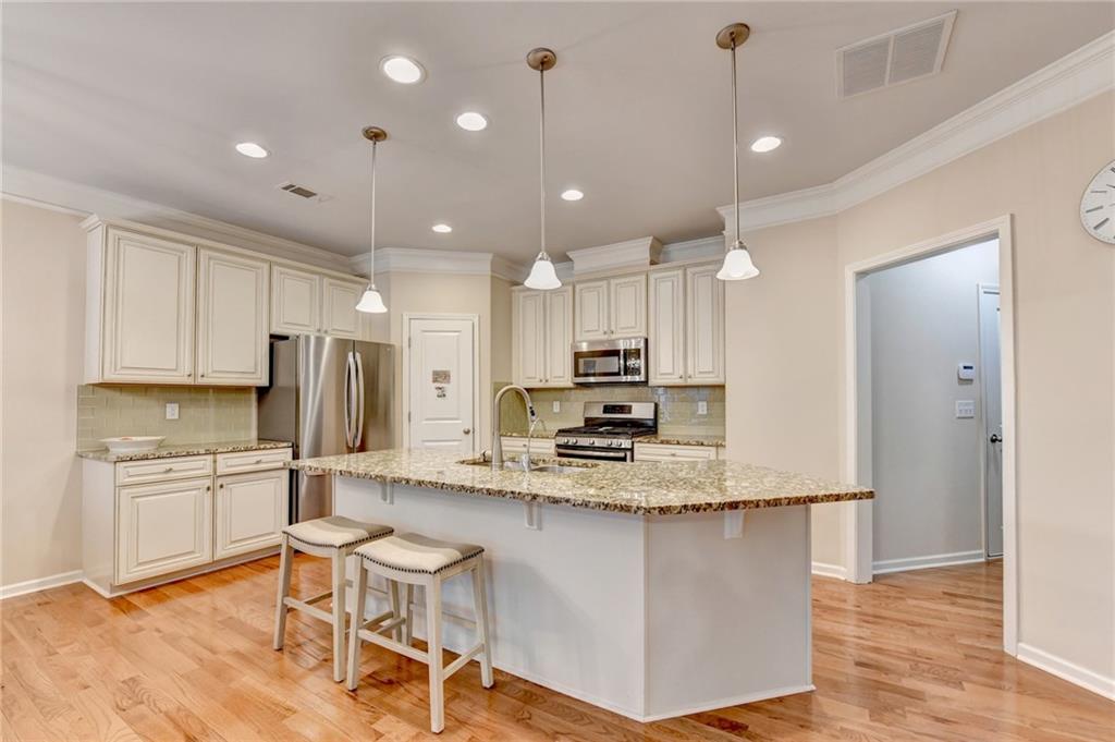 2455 Matlin Way Buford, GA 30519 - Photo 16 of 58 a kitchen with kitchen island granite countertop a refrigerator a stove a sink and white cabinets with wooden floor