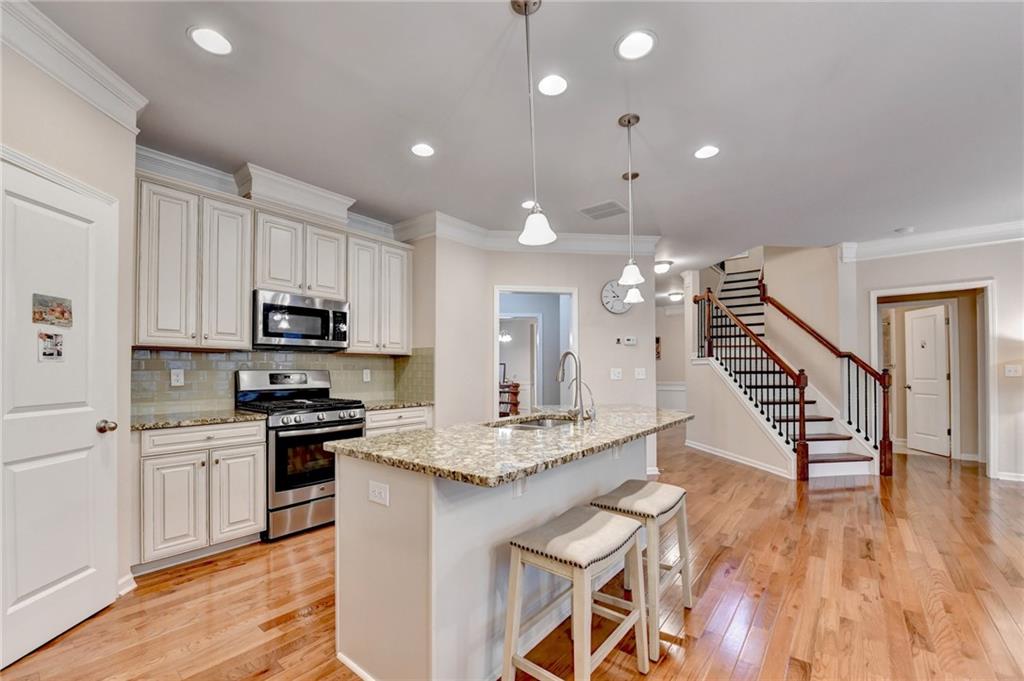 2455 Matlin Way Buford, GA 30519 - Photo 18 of 58 a kitchen with stainless steel appliances kitchen island granite countertop a stove a sink dishwasher and a refrigerator with wooden floor