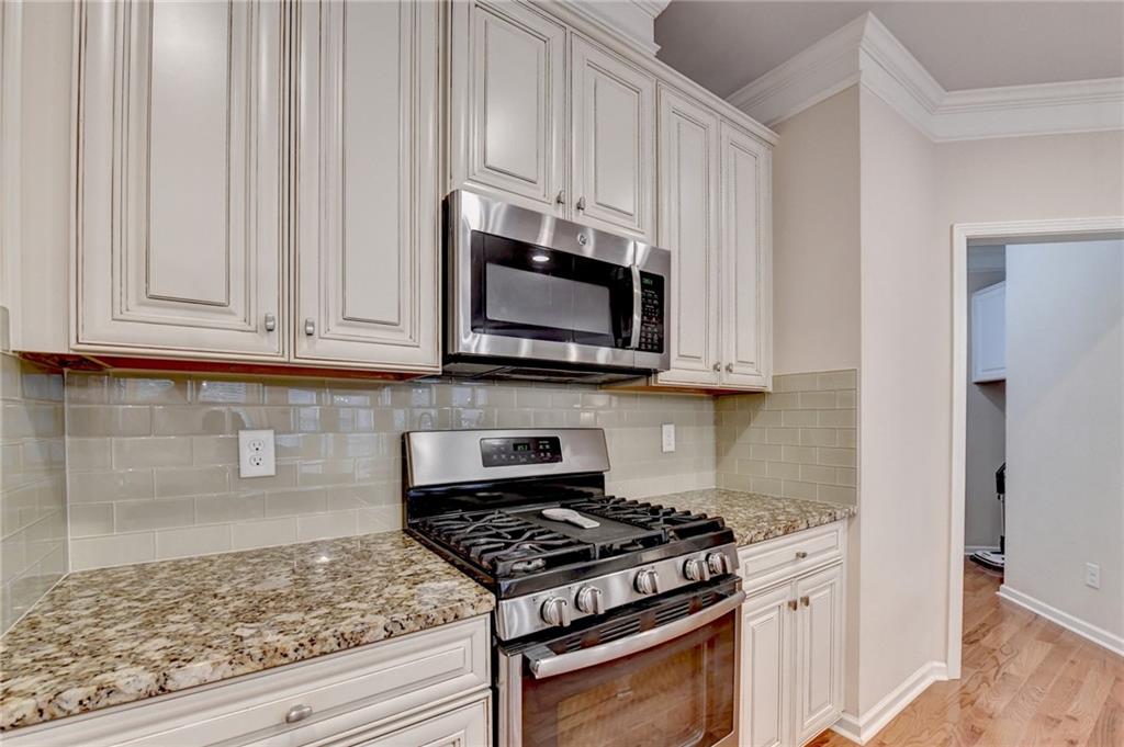 2455 Matlin Way Buford, GA 30519 - Photo 19 of 58 a kitchen with stainless steel appliances granite countertop a stove a microwave and a white cabinets