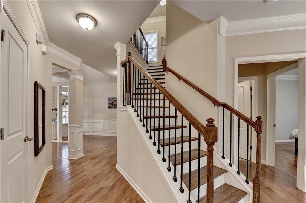 2455 Matlin Way Buford, GA 30519 - Photo 7 of 58 a view of staircase with wooden floor and a chandelier