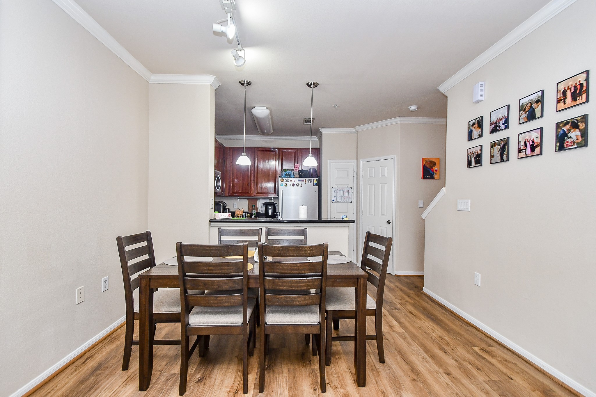 9200 Westheimer Road, Unit 1302 Houston, TX 77063 - Photo 12 of 29 This photo showcases a cozy dining area with wooden flooring, an elegant six-seater table set, and a view into a modern kitchen with pendant lighting and stainless steel appliances.