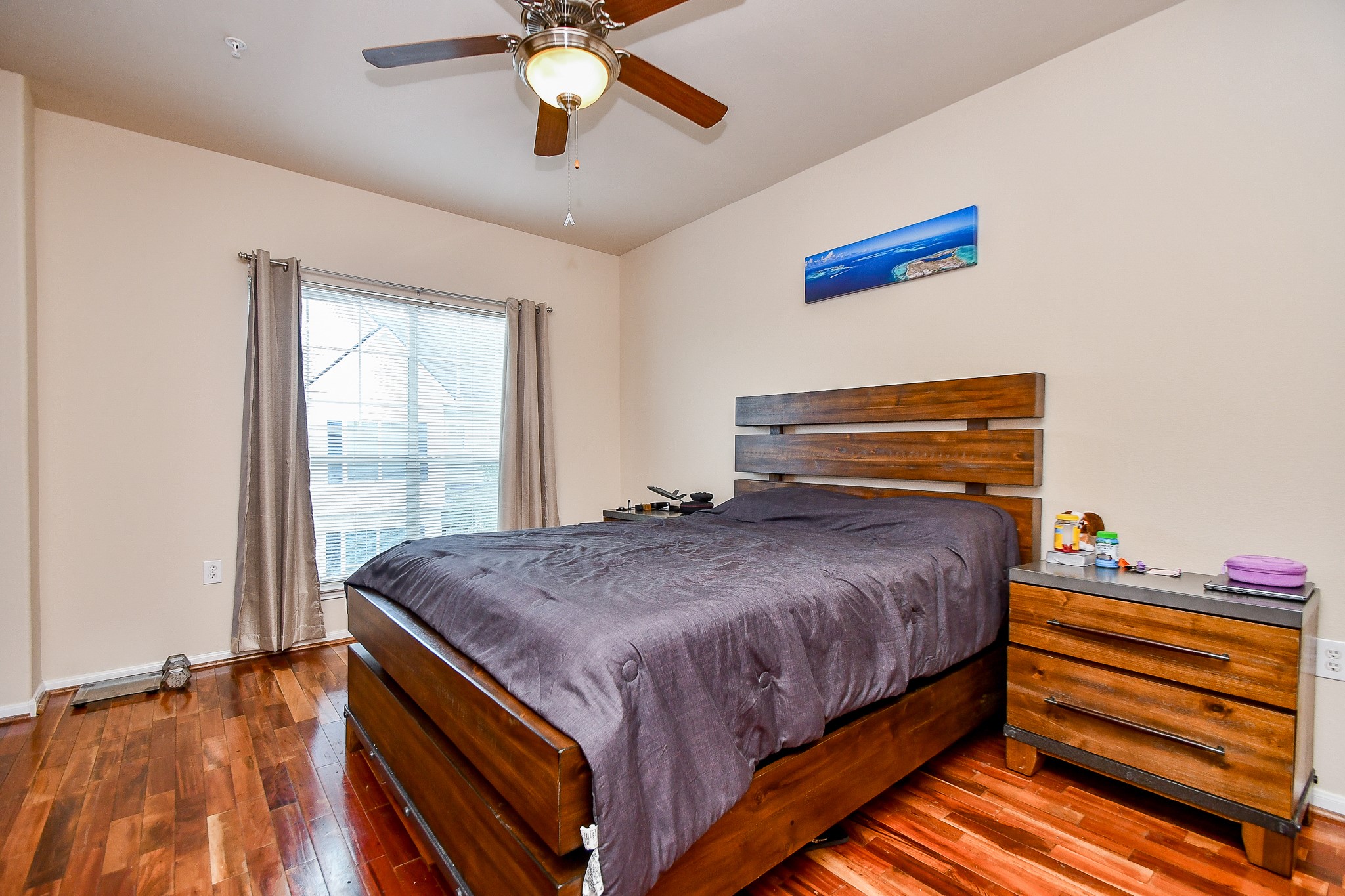 9200 Westheimer Road, Unit 1302 Houston, TX 77063 - Photo 23 of 29 This bedroom features polished hardwood floors, a ceiling fan, and a large window that lets in natural light.