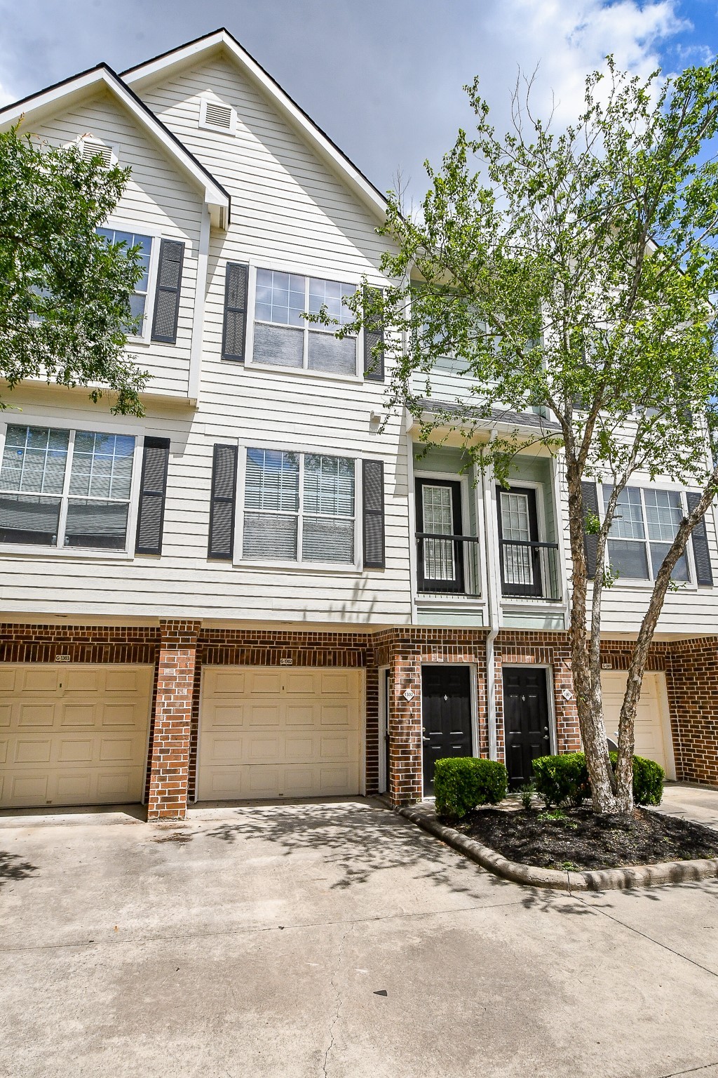 9200 Westheimer Road, Unit 1302 Houston, TX 77063 - Photo 6 of 29 This is a modern three-story townhouse with a brick and siding exterior. It features an attached garage, large windows, and a small landscaped area in front. The entrance is welcoming with double doors and the property is situated in a clean, well-maintained area.