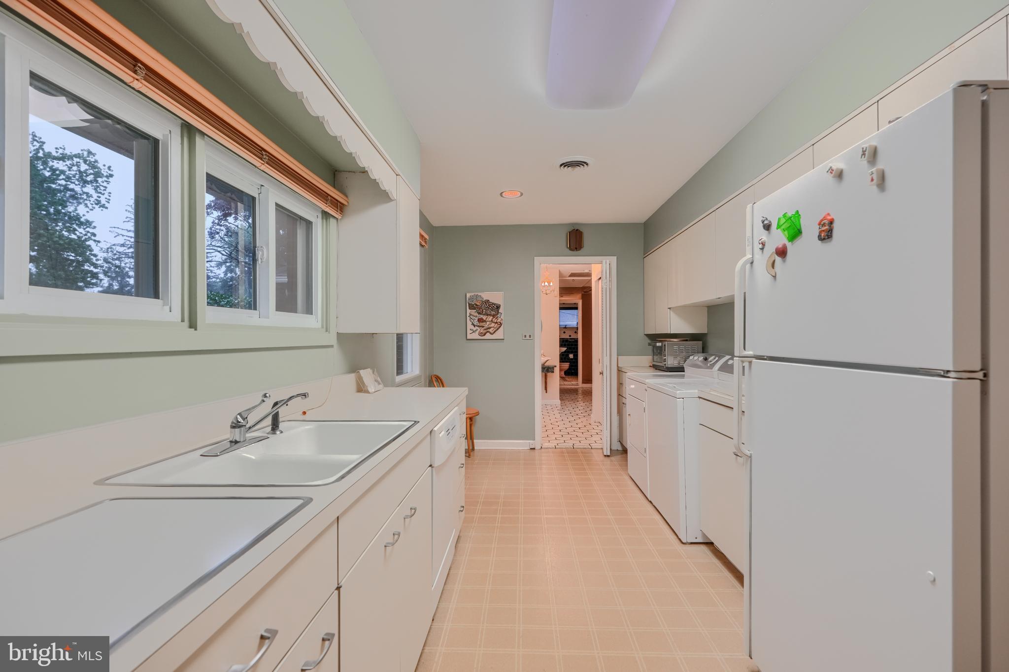 7900 Ivy Lane Baltimore, MD 21208 - Photo 8 of 32 a kitchen with a refrigerator a sink and dishwasher with white cabinets