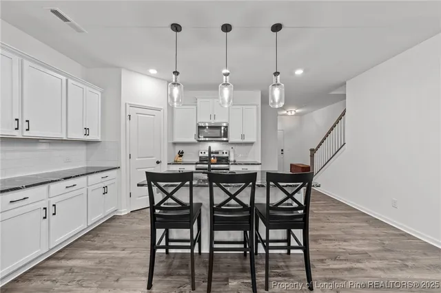a kitchen with stainless steel appliances granite countertop a dining table chairs sink and cabinets