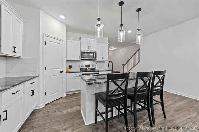 a kitchen with stainless steel appliances a white table chairs refrigerator and cabinets