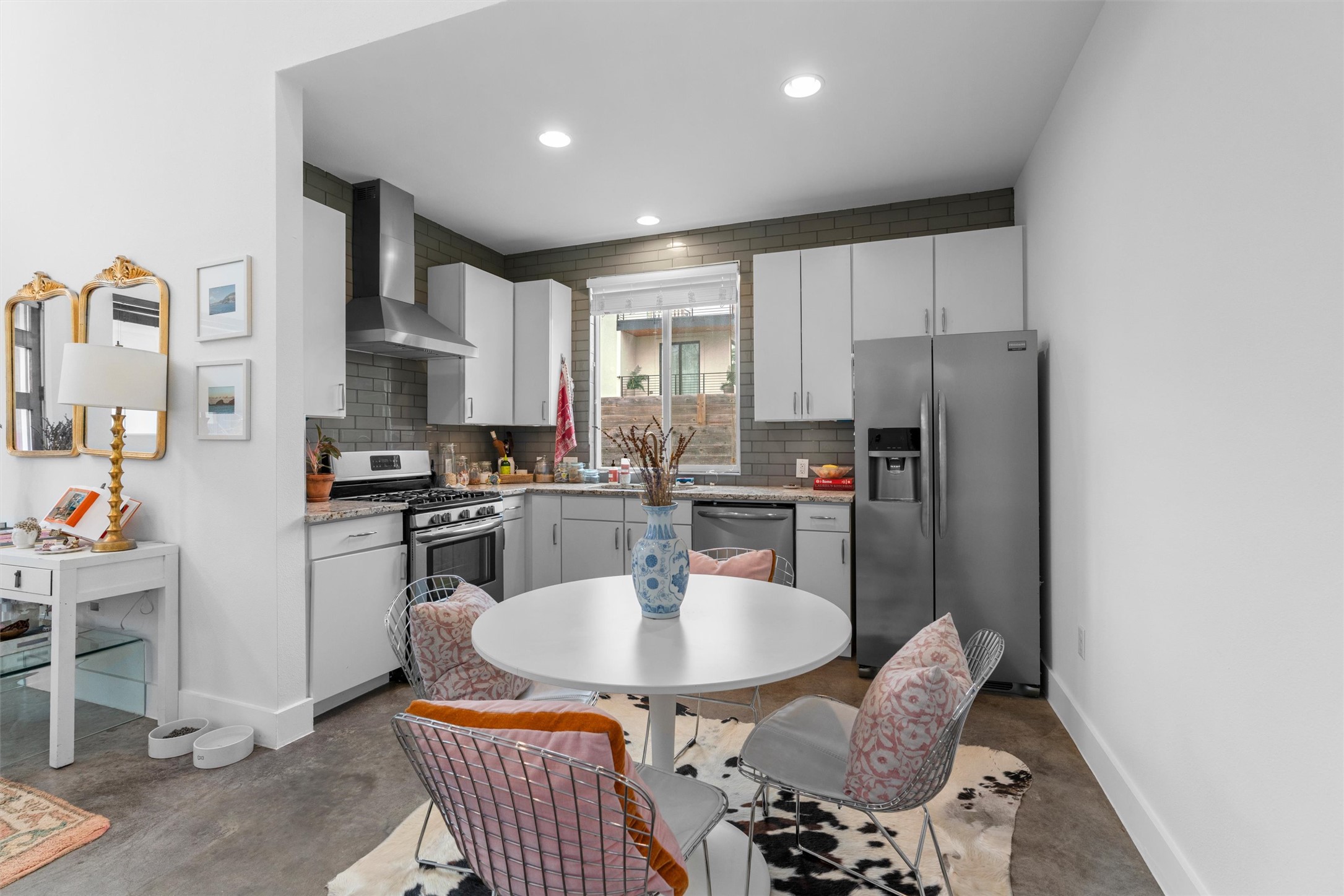 2514 East 4th Street, Unit B Austin, TX 78702 - Photo 6 of 22 a kitchen with stainless steel appliances granite countertop a stove a refrigerator a sink dishwasher a dining table and chairs with wooden floor