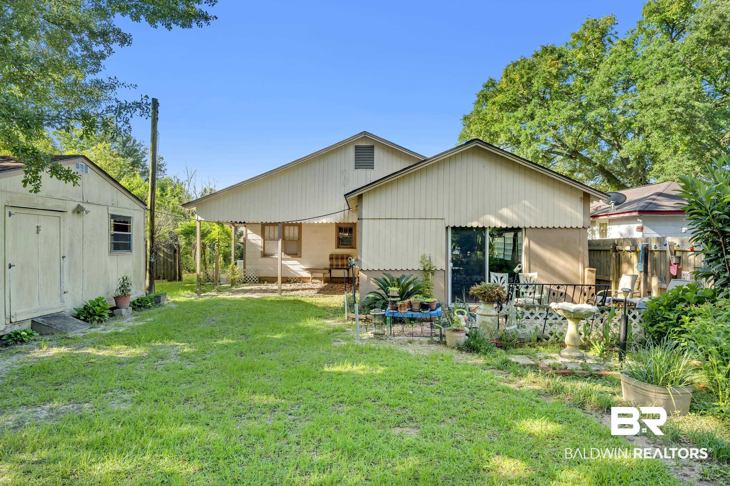 304 West Myrtle Avenue Foley, AL 36535 - Photo 22 of 29 Spacious backyard featuring a storage shed, a covered patio area, and an additional paved patio with sliding glass door access