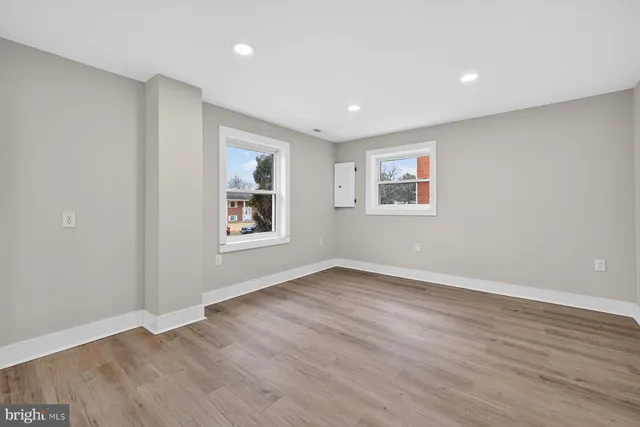a view of an empty room with window and wooden floor