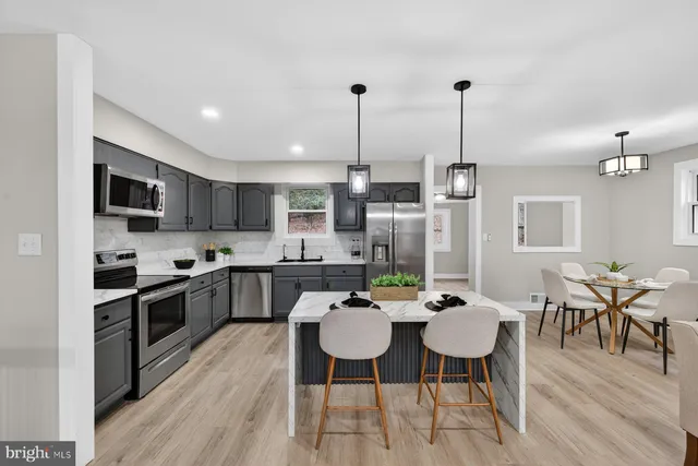 a kitchen with stainless steel appliances kitchen island granite countertop a dining table chairs stove a sink and dishwasher