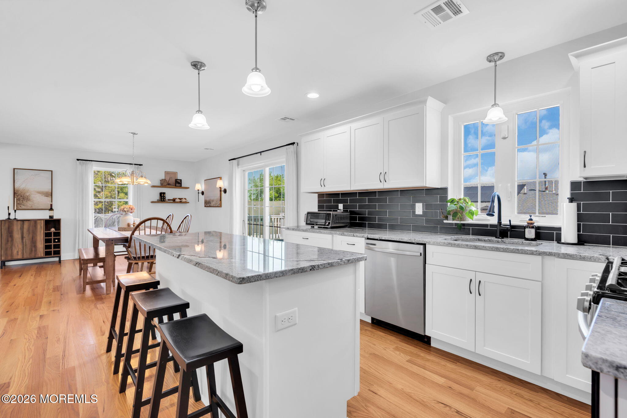 312 Beach Boulevard Forked River, NJ 08731 - Photo 22 of 40 a kitchen with stainless steel appliances kitchen island granite countertop a stove top oven a sink a dining table and chairs with wooden floor