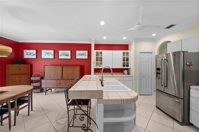 a dining hall with stainless steel appliances kitchen island granite countertop a dining table chairs and a refrigerator