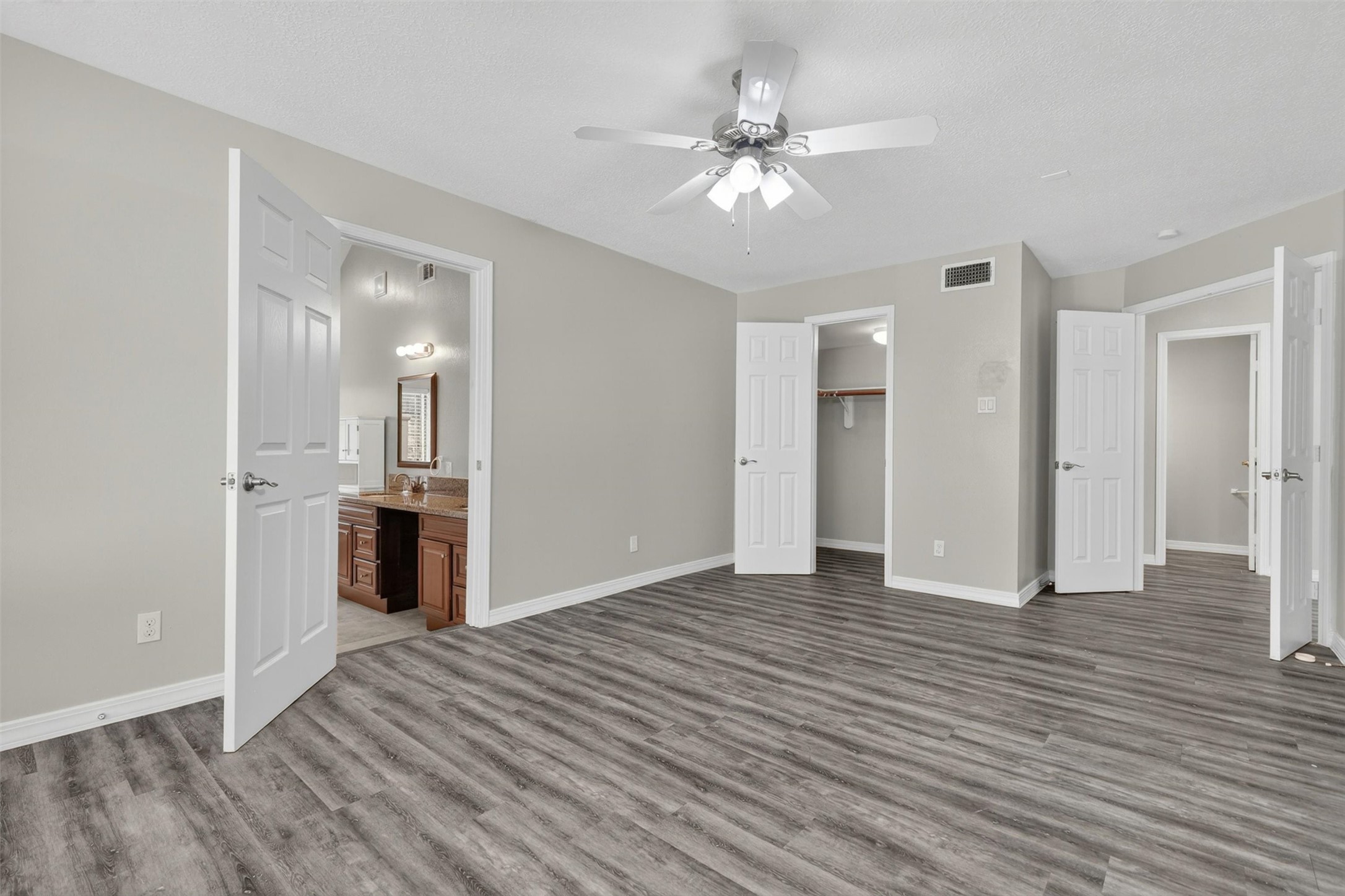 12929 Kingsbridge Lane Houston, TX 77077 - Photo 20 of 42 Spacious primary bedroom retreat featuring an oversized layout, modern flooring, and a bright open feel throughout. This inviting suite offers plenty of room for a king-sized bed, sitting area, or home office setup while maintaining a warm and relaxing atmosphere. Buyers will love the direct access to the en-suite bathroom, generous closet space, neutral designer colors, and move-in ready condition.