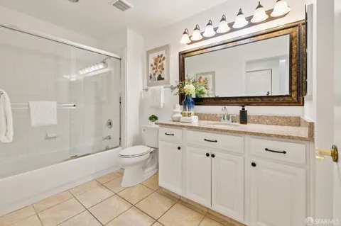 a bathroom with a granite countertop sink a toilet and shower