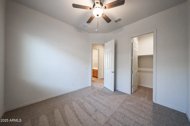 a view of an empty room and chandelier fan