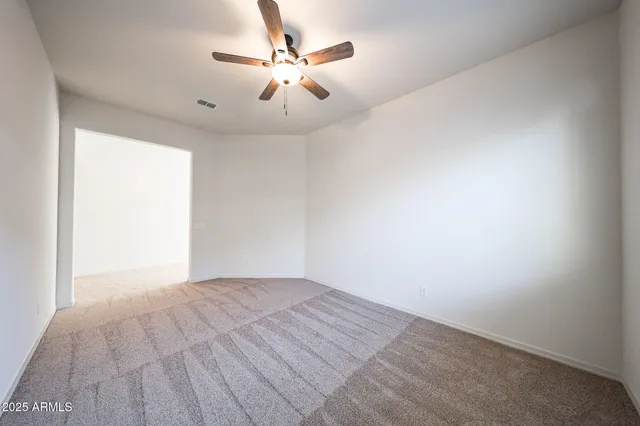 an empty room with a chandelier fan and windows