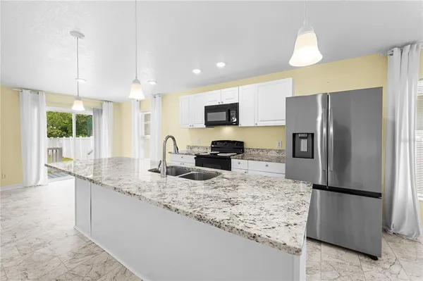 a kitchen with stainless steel appliances granite countertop a stove a sink dishwasher a refrigerator and a microwave