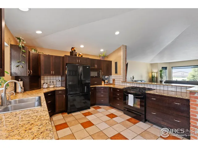 a kitchen with stainless steel appliances kitchen island granite countertop a sink stove and refrigerator