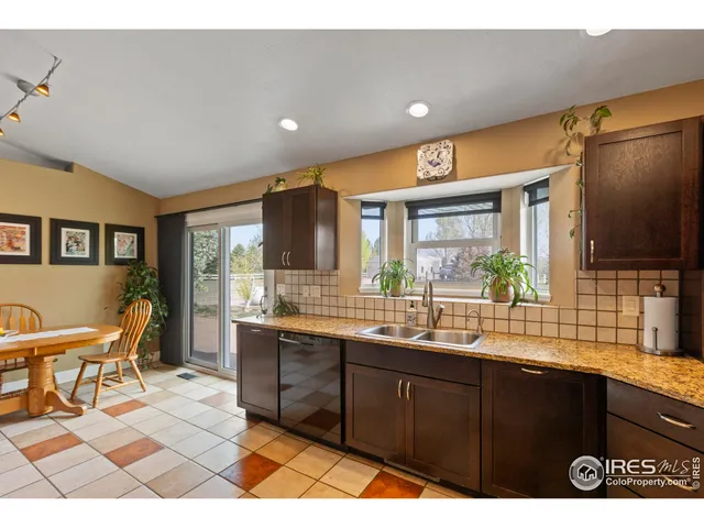 a dining hall with stainless steel appliances granite countertop a sink dishwasher a dining table and chairs with wooden floor