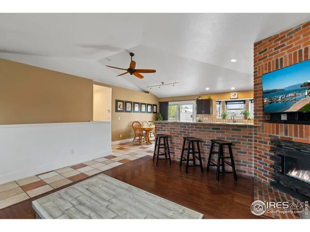 a living room with stainless steel appliances furniture a fireplace and a kitchen view